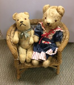 Costumed teddy bear couple on wicker settee